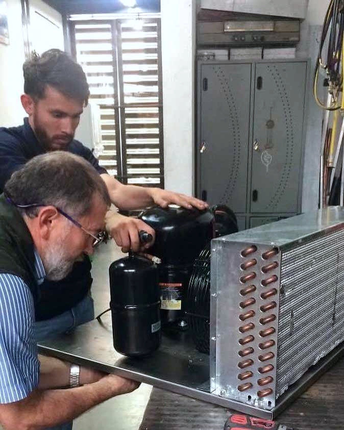 Técnicos revisando un compresor y un condensador