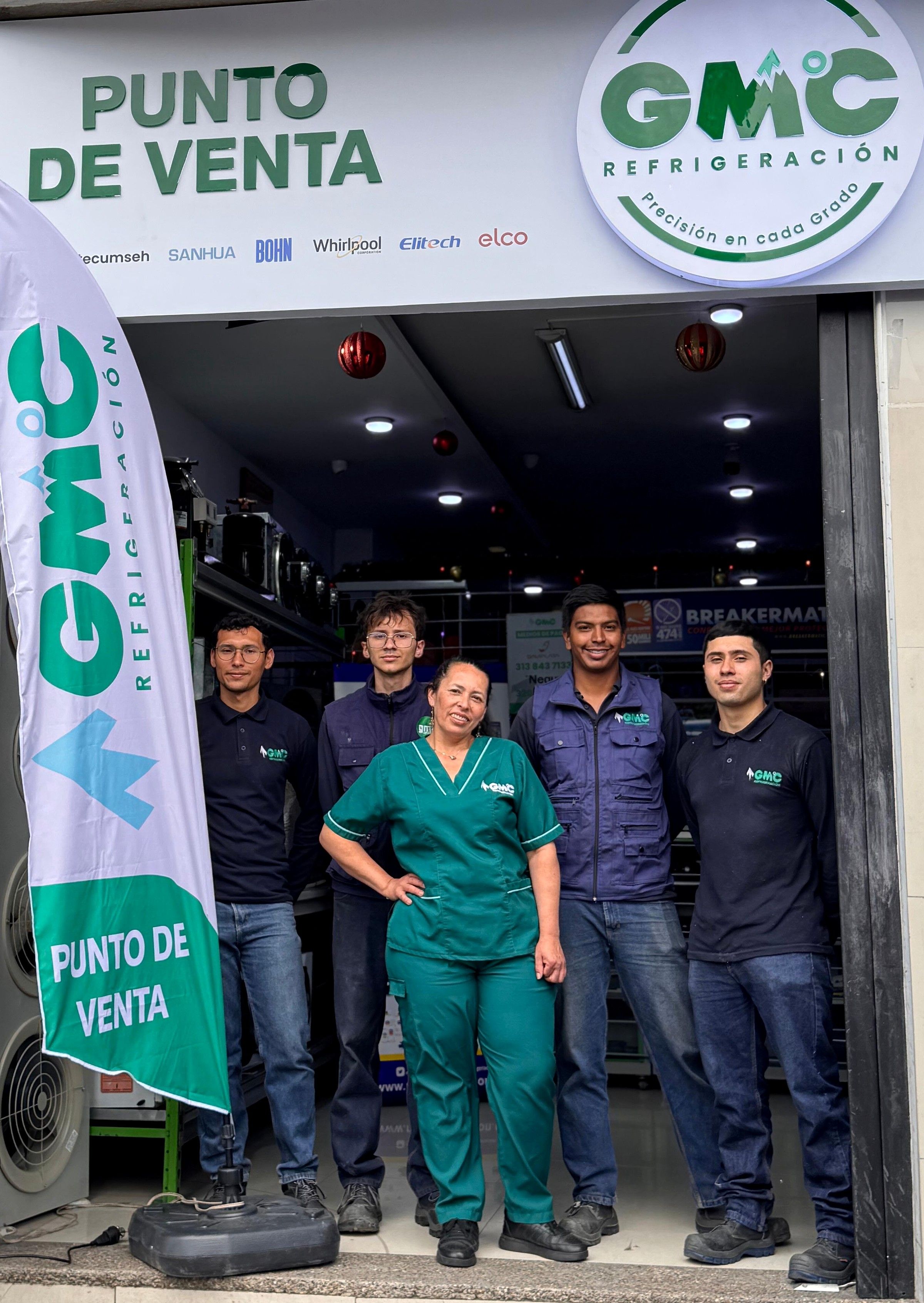 Cinco integrantes del equipo técnico de GMC con uniforme de la empresa, frente al aviso del punto de venta de GMC Refrigeración en Bogotá