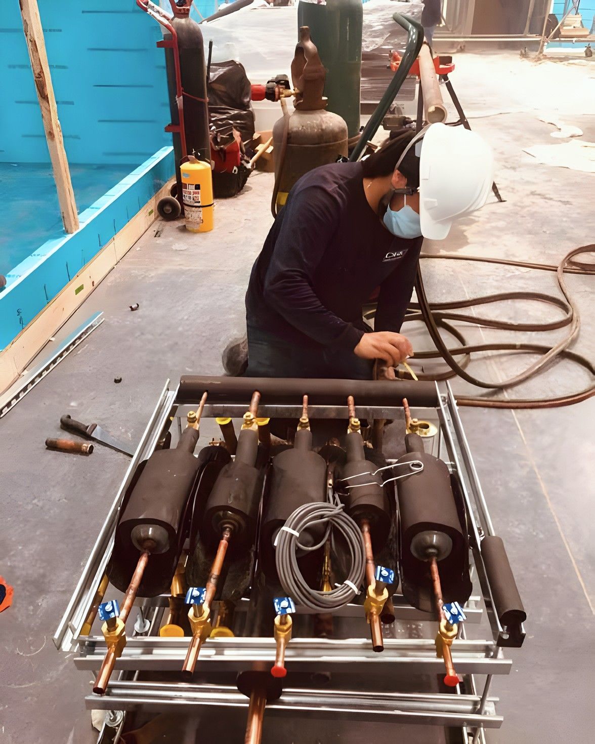 Técnico armando la tubería de un rack de compresores